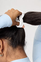Detalle del scrunchie Scrunch & Glow blanco para el cabello